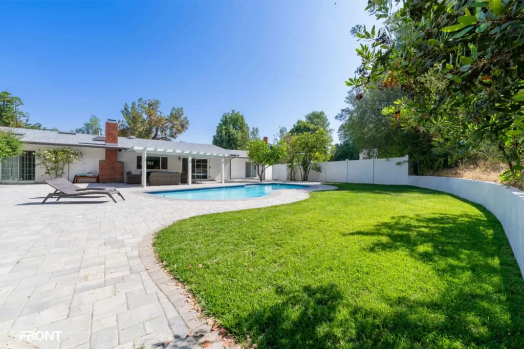 Resort-style backyard remodel in Tarzana, with a freeform pool, paver deck and louvered white pergola — photo 3 of 20