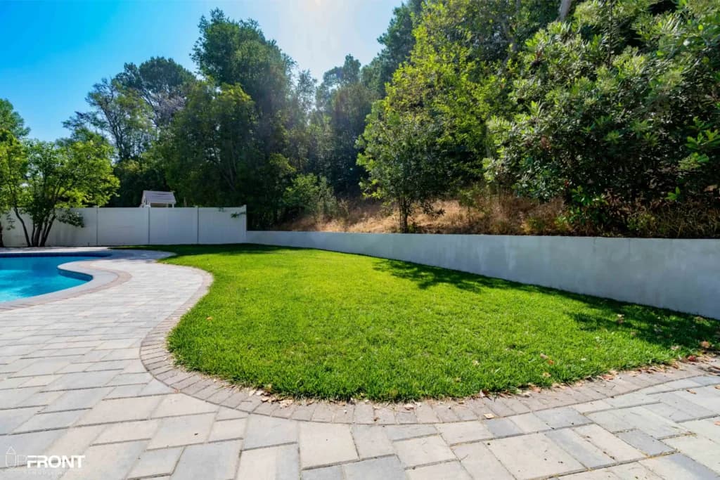 Resort-style backyard remodel in Tarzana, with a freeform pool, paver deck and louvered white pergola — photo 4 of 20