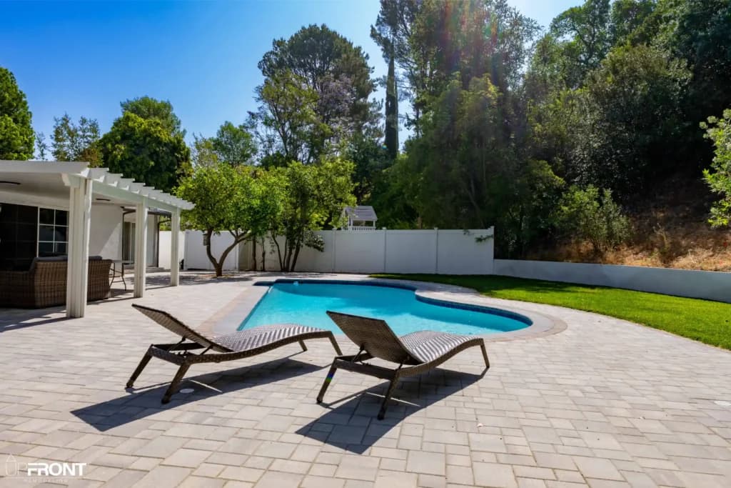 Resort-style backyard remodel in Tarzana, with a freeform pool, paver deck and louvered white pergola — photo 5 of 20