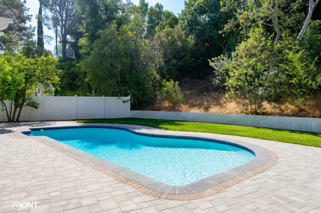 Resort-style backyard remodel in Tarzana, with a freeform pool, paver deck and louvered white pergola — photo 11 of 20