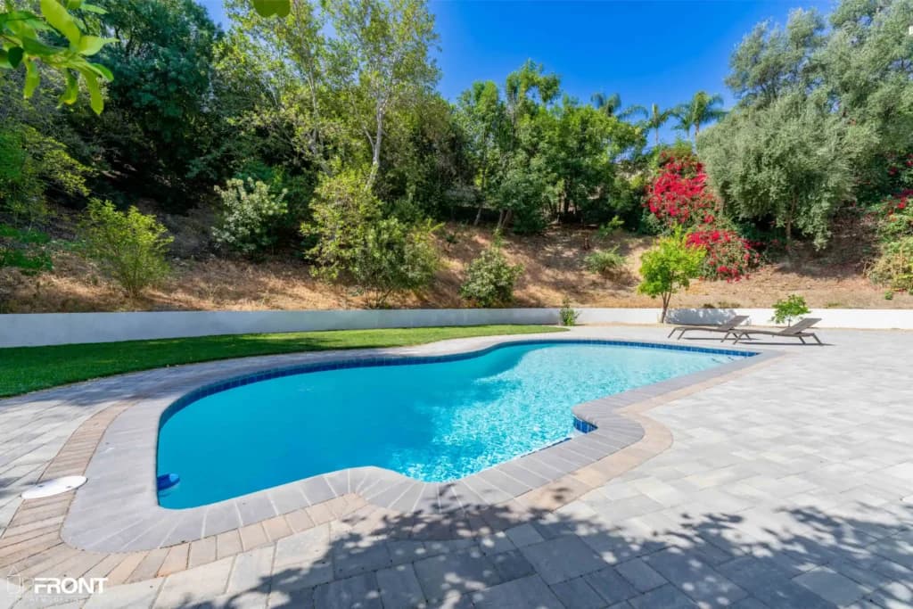 Resort-style backyard remodel in Tarzana, with a freeform pool, paver deck and louvered white pergola — photo 12 of 20