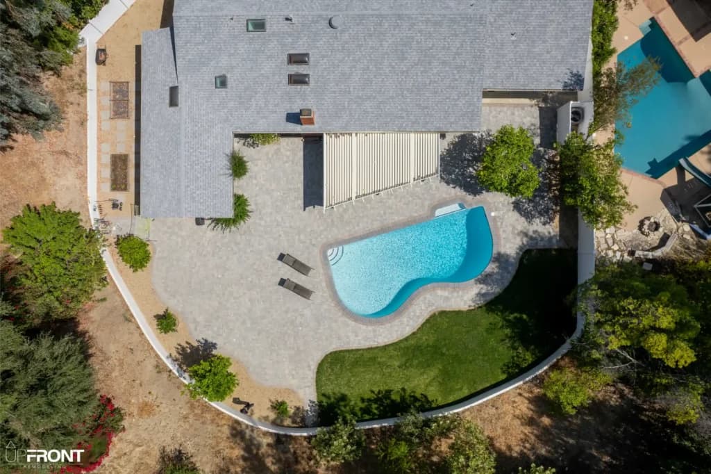 Resort-style backyard remodel in Tarzana, with a freeform pool, paver deck and louvered white pergola — photo 17 of 20