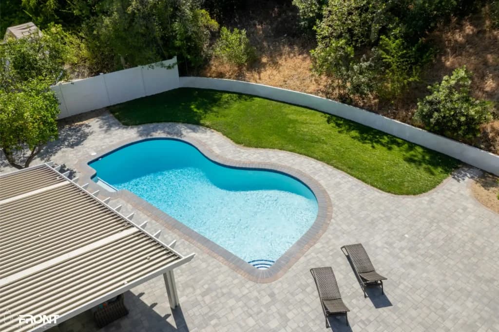 Resort-style backyard remodel in Tarzana, with a freeform pool, paver deck and louvered white pergola — photo 18 of 20