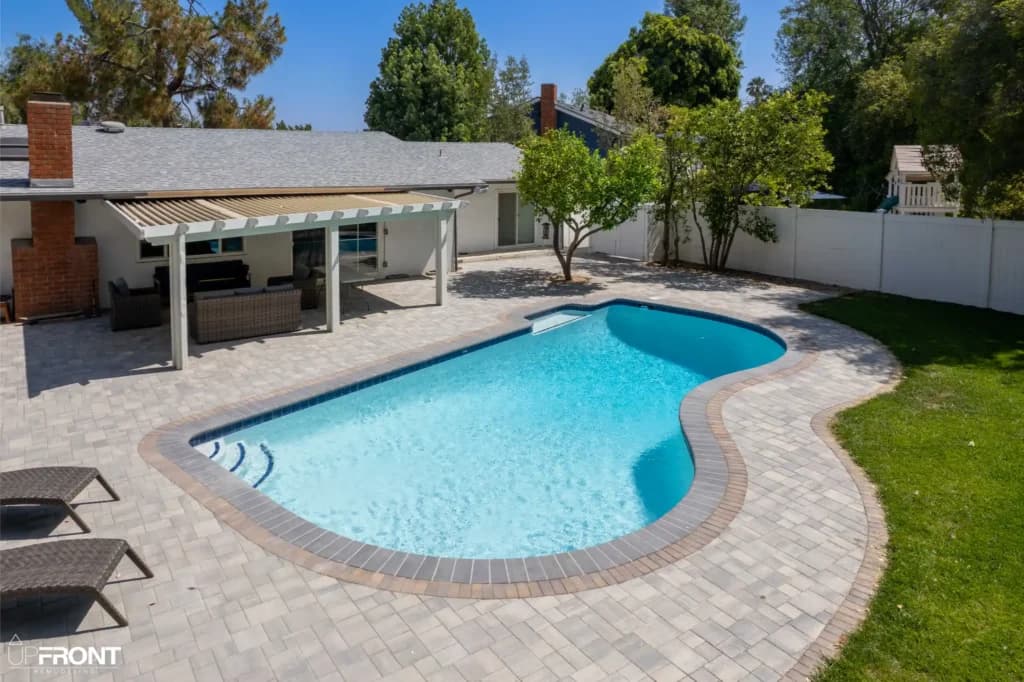 Resort-style backyard remodel in Tarzana, with a freeform pool, paver deck and louvered white pergola — photo 19 of 20