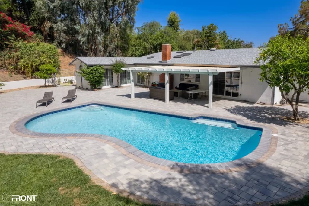 Resort-style backyard remodel in Tarzana, with a freeform pool, paver deck and louvered white pergola — photo 20 of 20